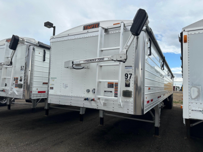 Timpte hopper trailer with 66 inch sides, white exterior, chassis legs visible, hydraulic tailgate, model Thunder 7000 label on front, side rails and reflectors.