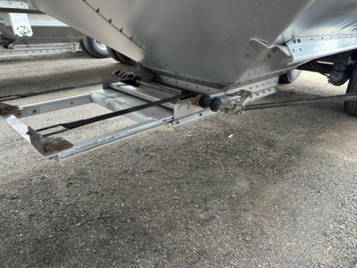 Trailer undercarriage showing hitch frame and suspension components of a Timpte hopper trailer, aluminum frame with bolts and spring mechanism visible.