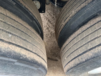 Two large rear tires of a Timpte Super Hopper trailer viewed from between wheels, showing dirt on tires and wheel hubs.