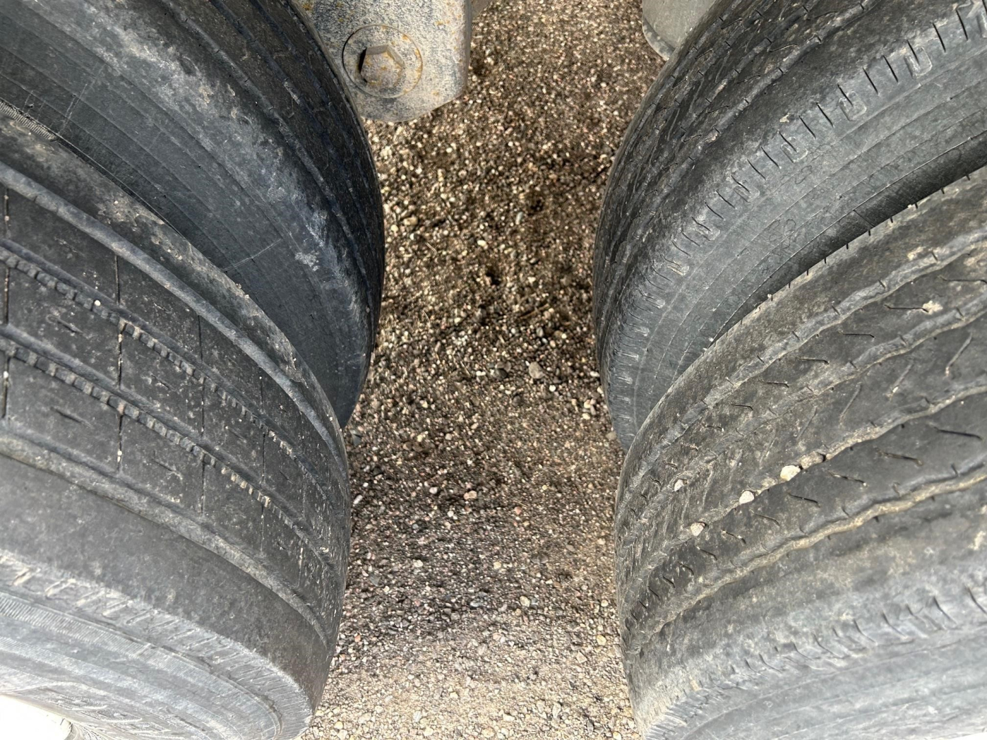 Two large trailer tires viewed from above with gravel beneath. No readable text visible on the image itself.