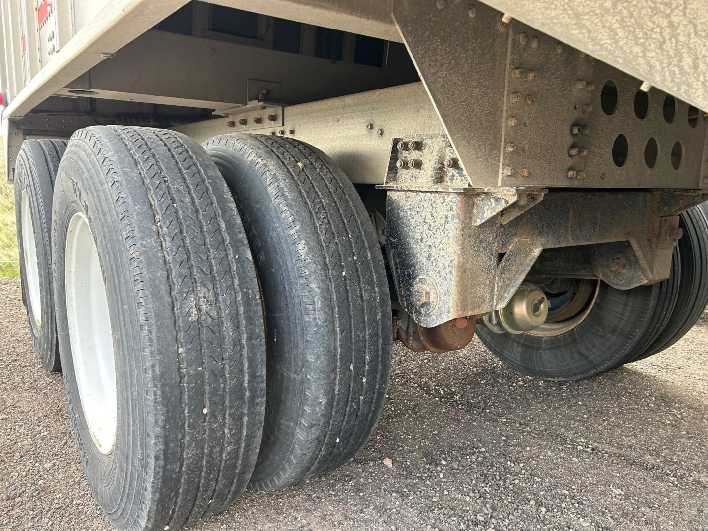 Cornhusker air ride grain hopper trailer axle and suspension with dual rear tires and undercarriage components.