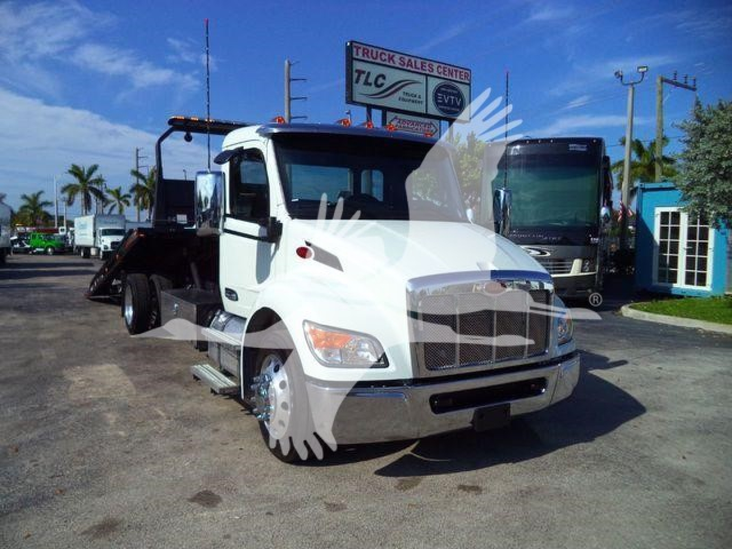 Truck with rollback bed and white cab, front view, Peterbilt 536 at dealership lot.