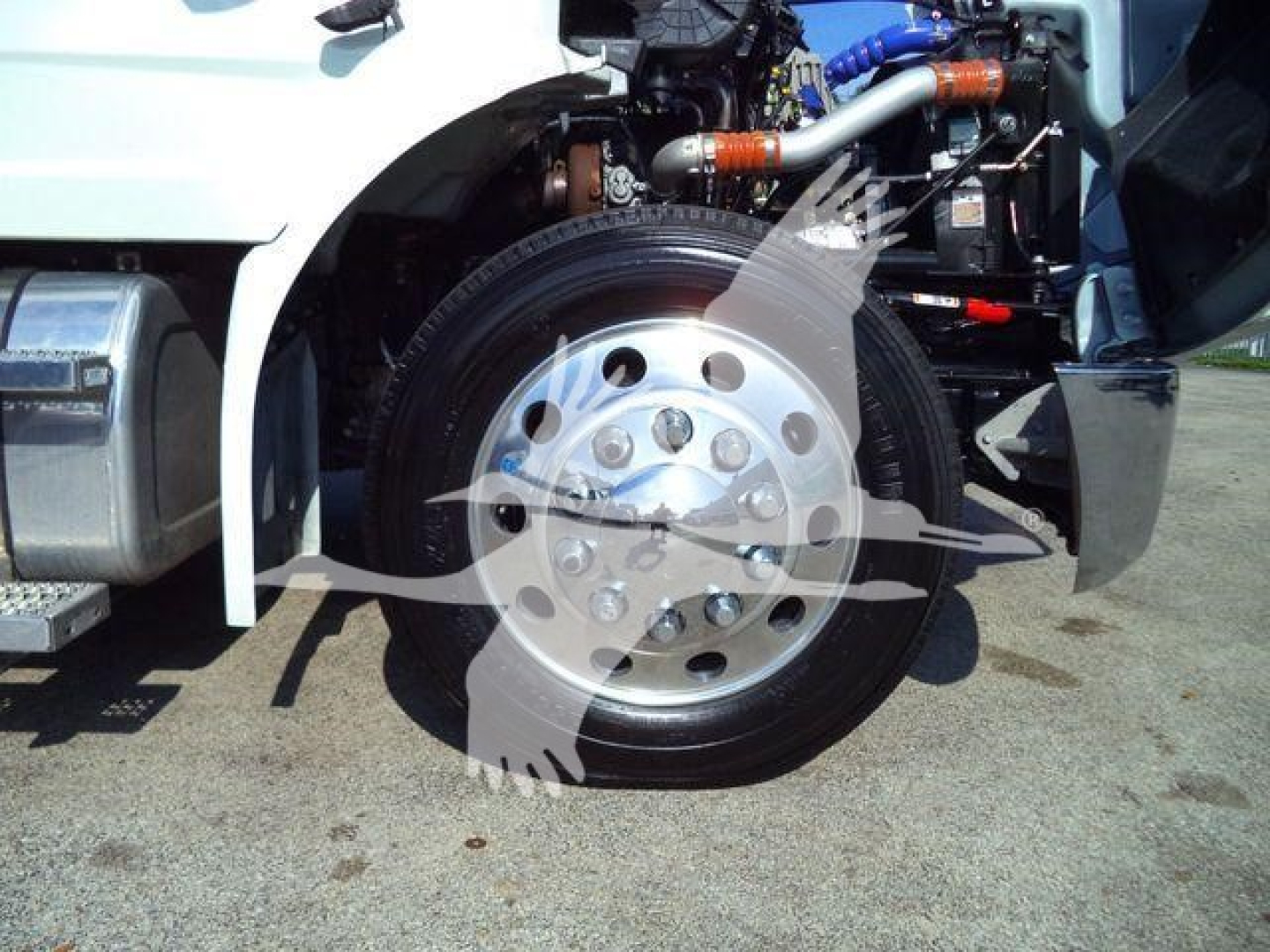 Peterbilt 536 rollback truck front wheel and suspension components visible, chrome wheel with lug nuts, engine bay visible with hoses and components.