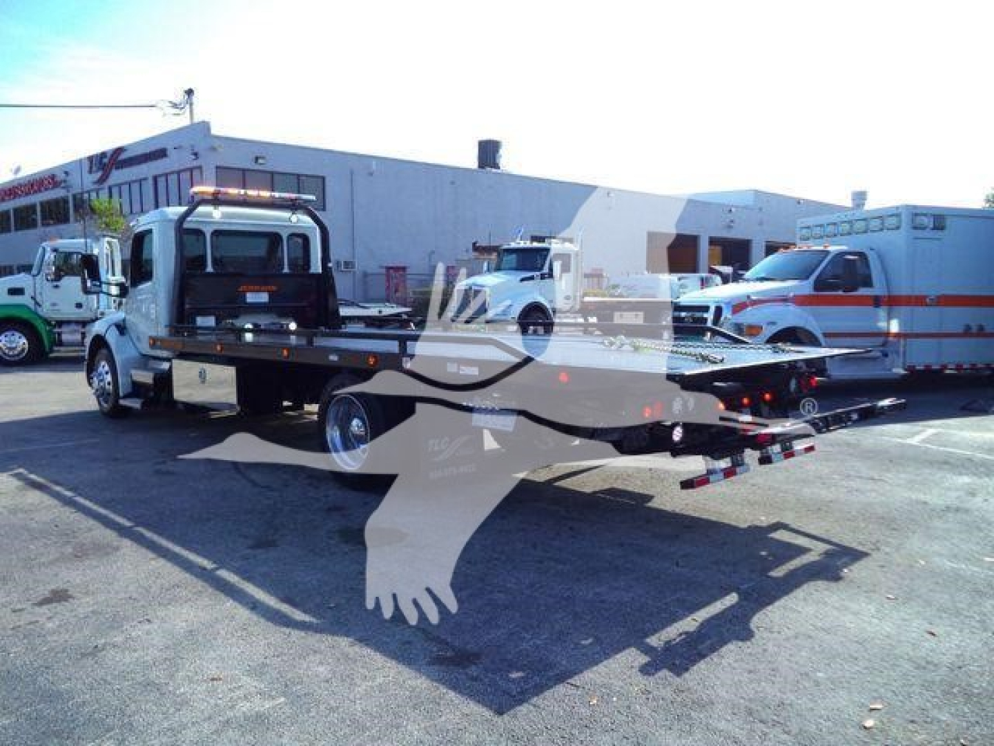 Peterbilt 536 rollback tow truck with flatbed in service lot showing cab and extended flatbed, stock number 1PETE536XLP22.