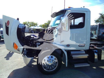 Peterbilt 536 rollback truck with engine cover open showing front wheel and cab, white exterior, chrome wheel, exposed engine bay.