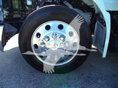 Peterbilt 536 rollback truck wheel close-up showing polished chrome hub and tire; part of white cab visible; stock number and listing context not shown on image
