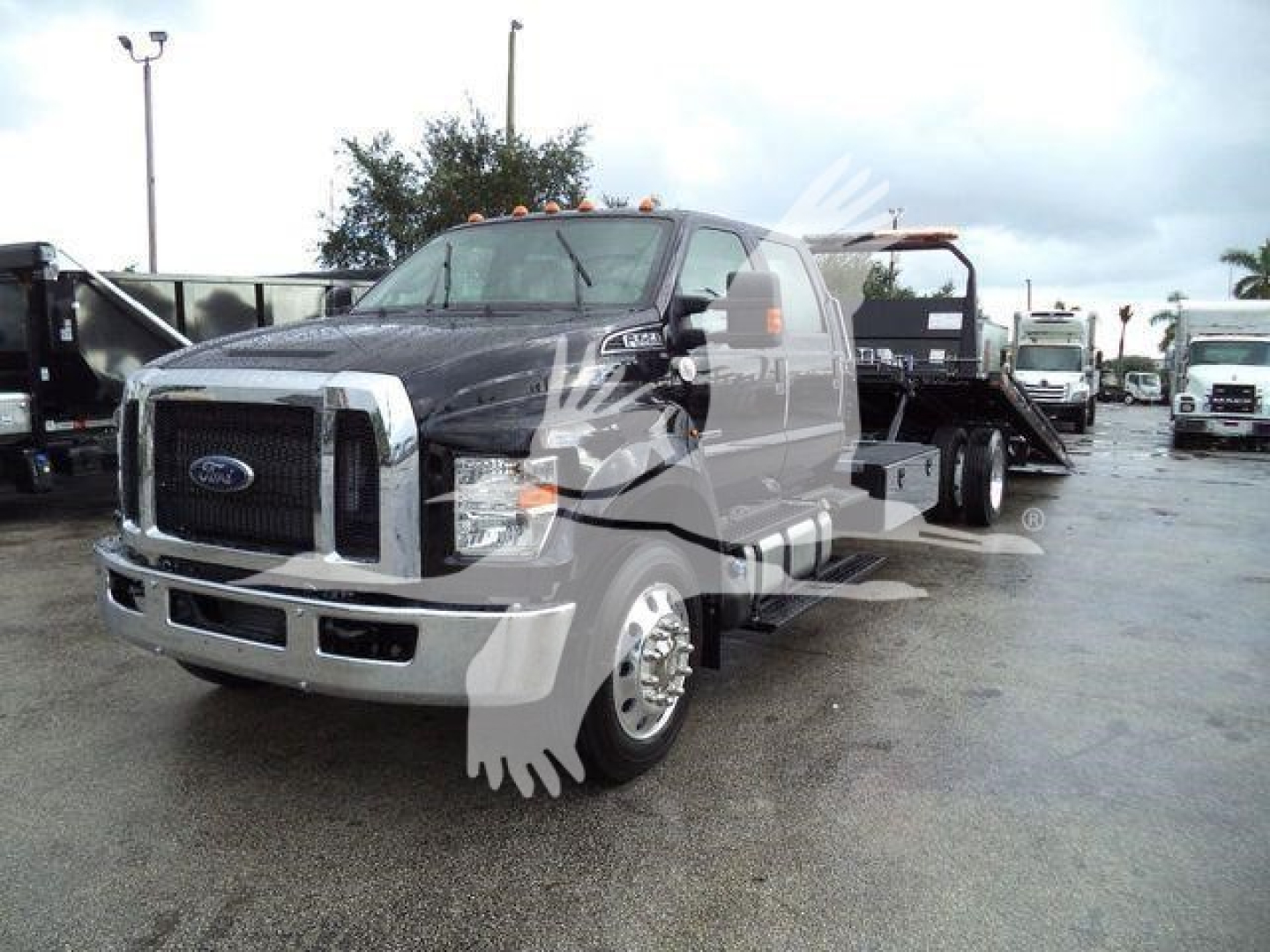 Ford F-750 SD rollback truck front-left view showing cab and flatbed, with visible Ford grille and headlights.