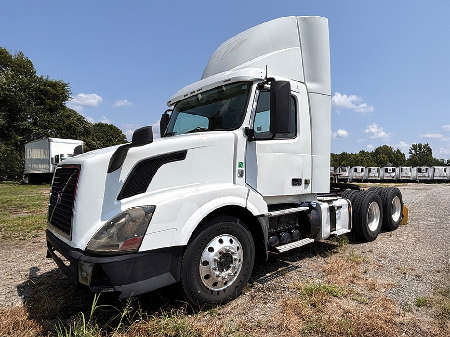 Volvo VNL 300 conventional daycab truck in white with sleeper cab, three-axle rear, front left view.
