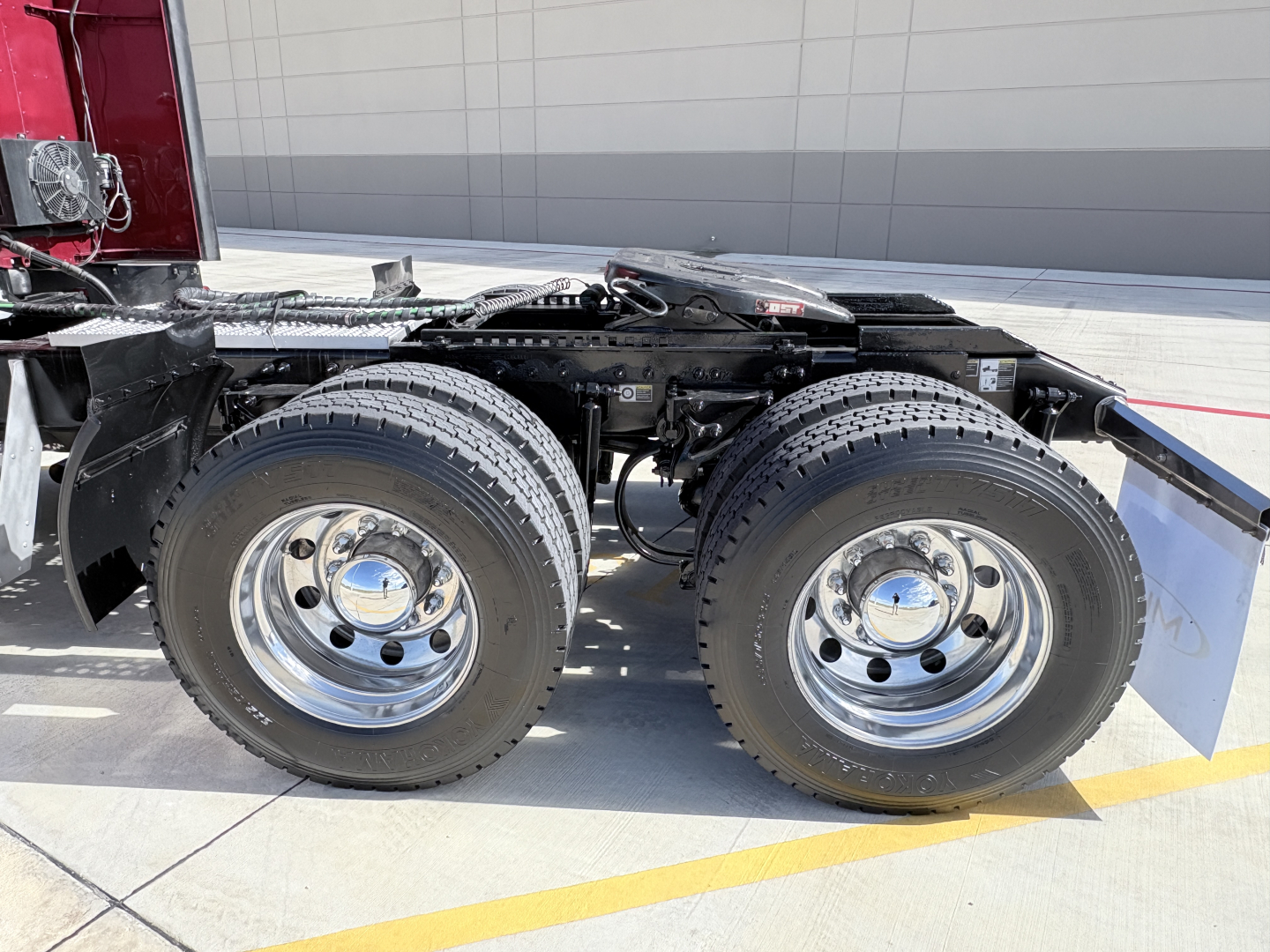 Peterbilt 579 truck chassis showing dual rear axles with chrome wheels and tires, undercarriage visible, side view of cabless tractor section.
