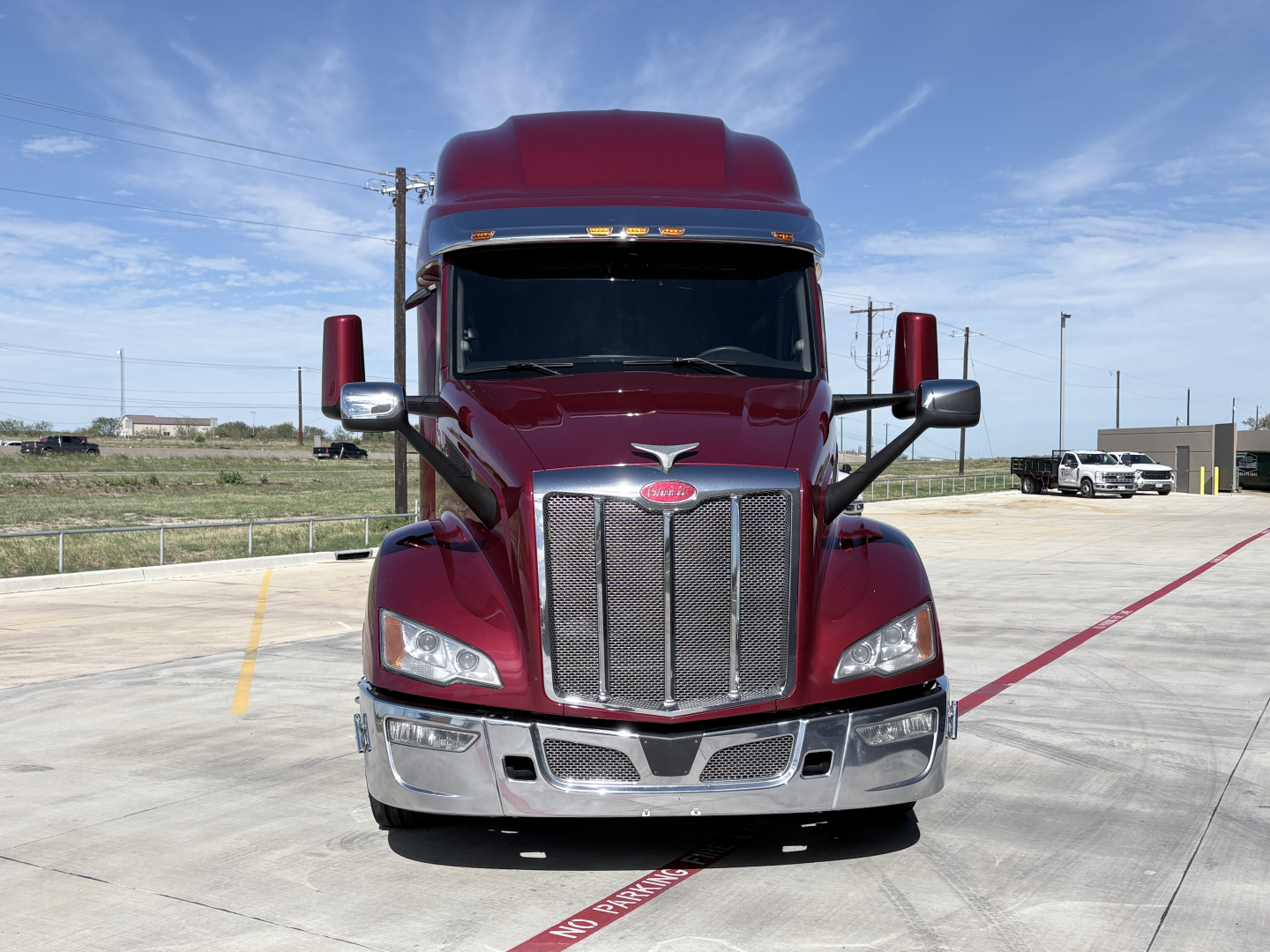 Peterbilt 579 conventional sleeper truck front view showing chrome grille, large bumper, and maroon paint.