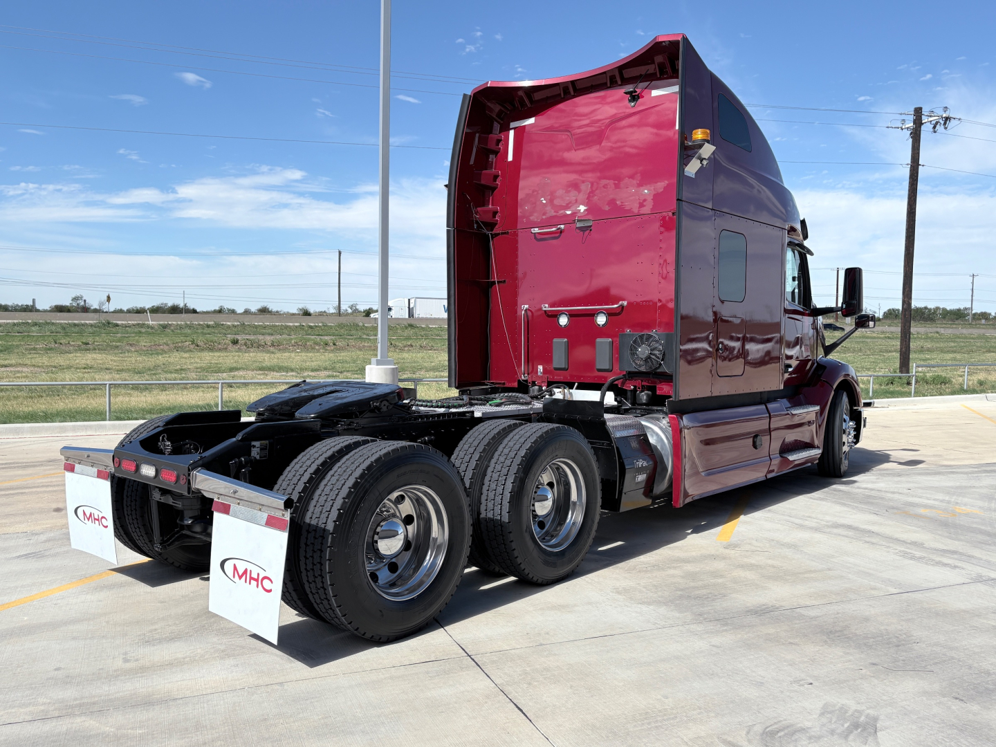 Peterbilt 579 tractor in burgundy, rear-three-quarter view showing dual rear axles and sleeper cab, no visible text on side panels.