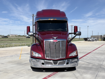 Peterbilt 579 truck front view showing chrome grille, maroon cab, large windshield, dual mirrors, and bumper.