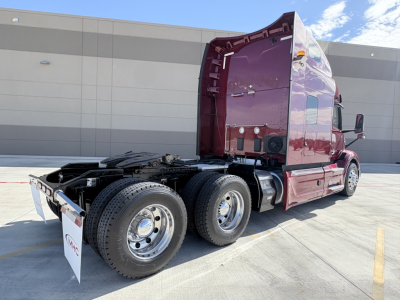 Peterbilt 579 tractor with maroon sleeper cab, rear view showing dual rear axles and fifth wheel.