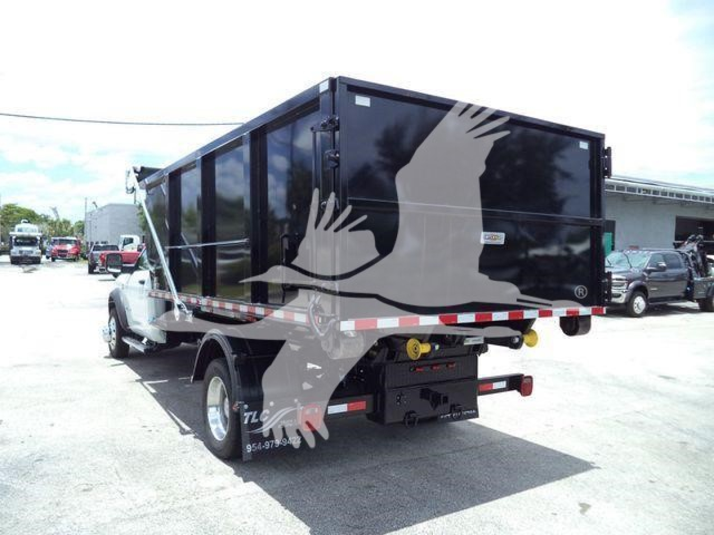 Side/rear view of a new 2024 Ram 5500 SLT dump/roll-off truck with a black cargo container. Visible text includes stock number DSL550014SNG2.