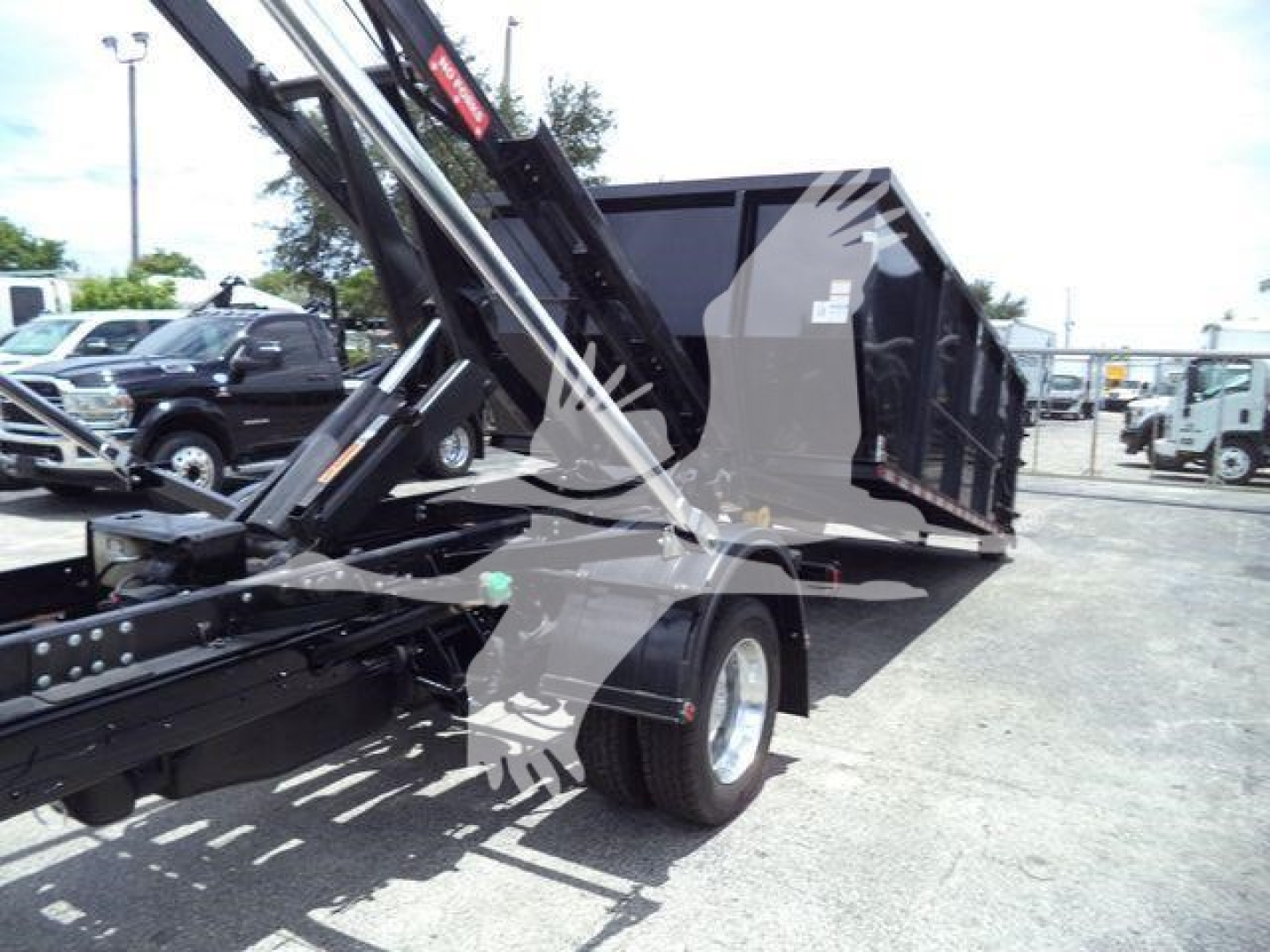 Ram 5500 dump-bed truck with hydraulic lift and roll-off body, side view showing rear wheels and cargo bed.