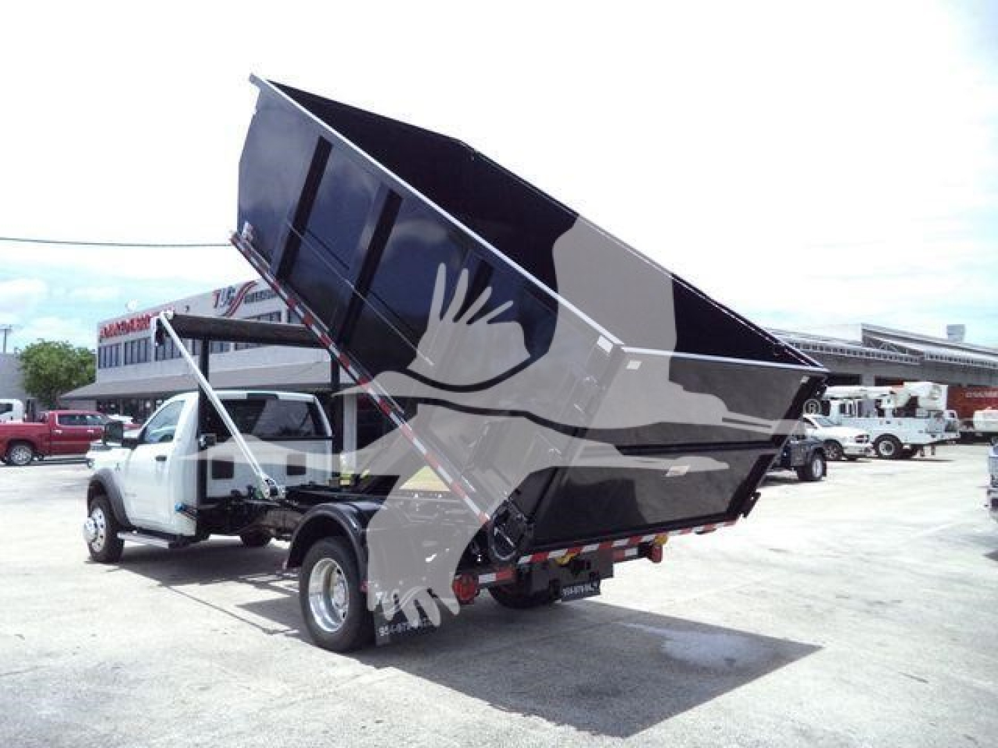 Ram 5500 dump truck raised bed view showing truck with dumping cargo bed and cab in a dealership lot.