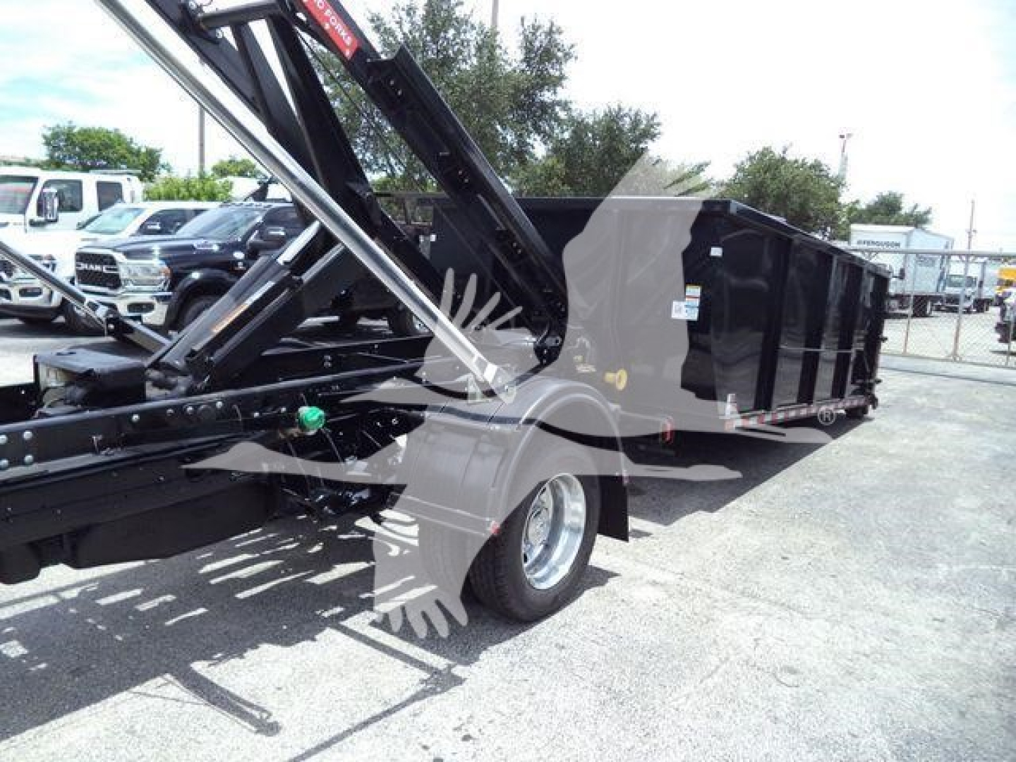 Ram 5500 dump truck in-service showing roll-off hoist and cargo bed with hydraulic arms and wheel.