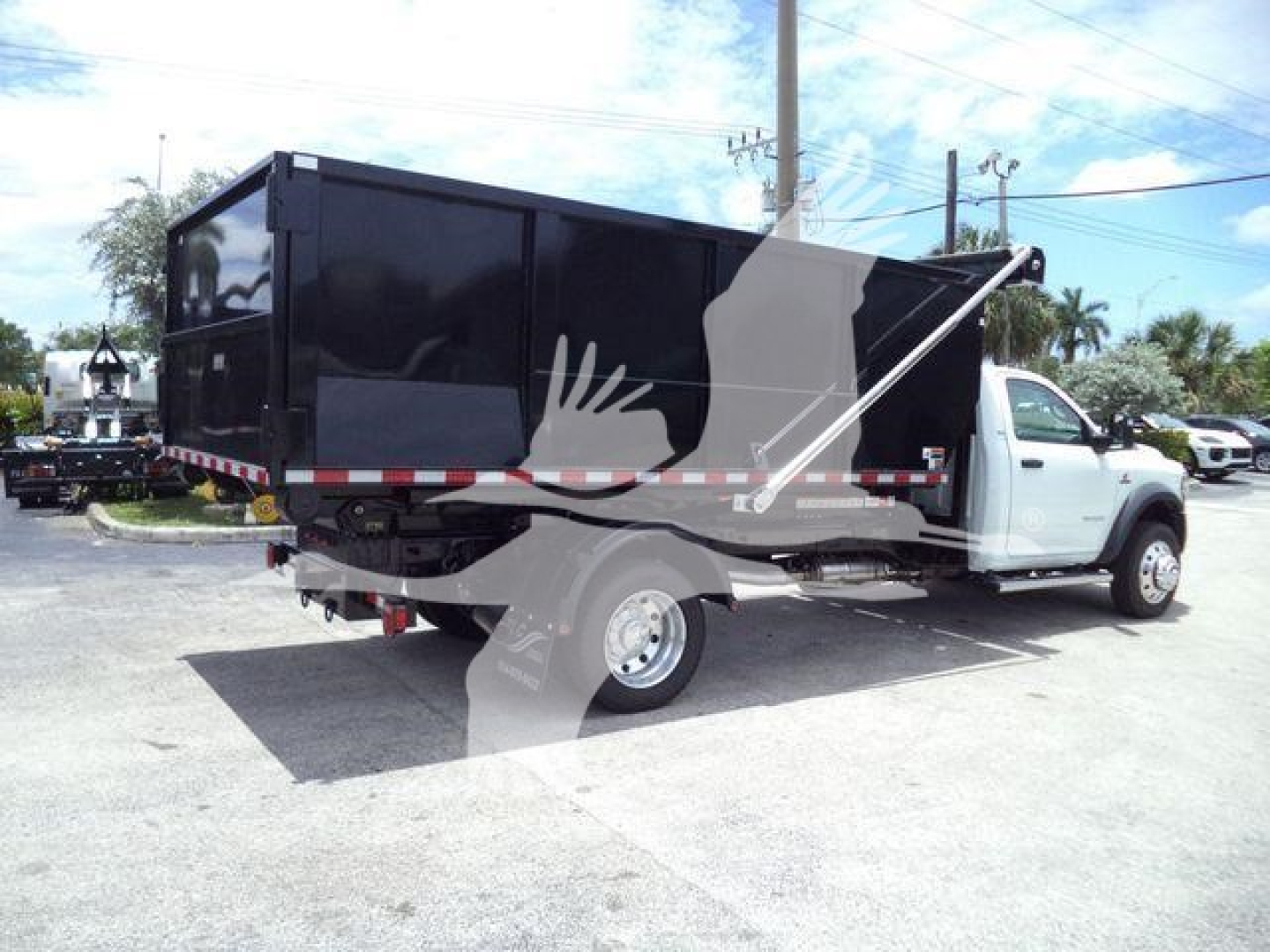 Ram 5500 dump body truck side view showing solid black dump bed and white cab, rollover truck with side view of rear.