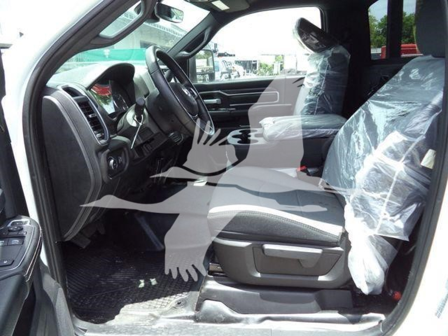 Ram 5500 interior cab view from driver side showing front seats wrapped in plastic, steering wheel, dashboard, and open door.