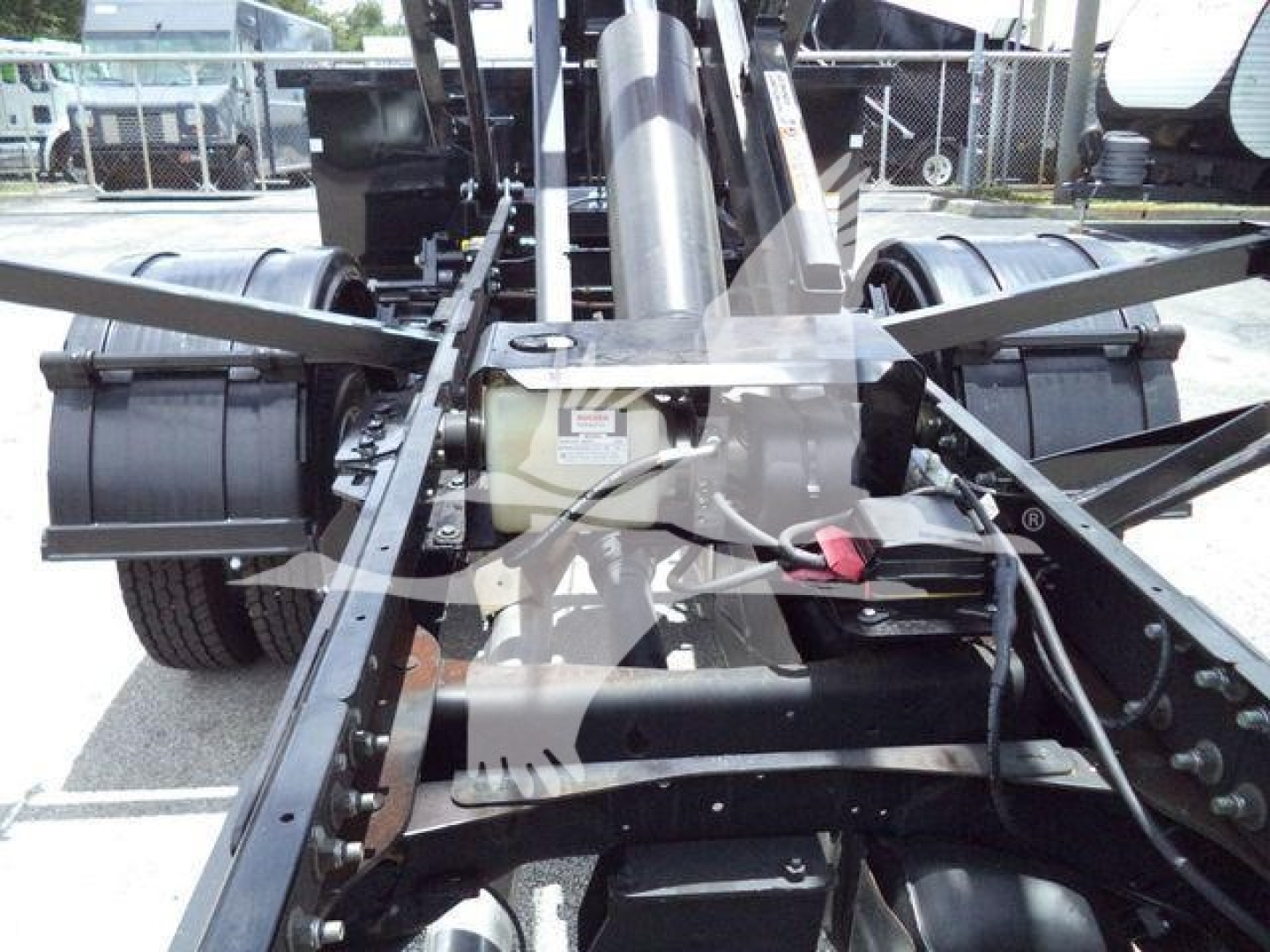 Ram 5500 roll-off truck chassis showing hydraulic PTO and frame rails with components and hoses visible.