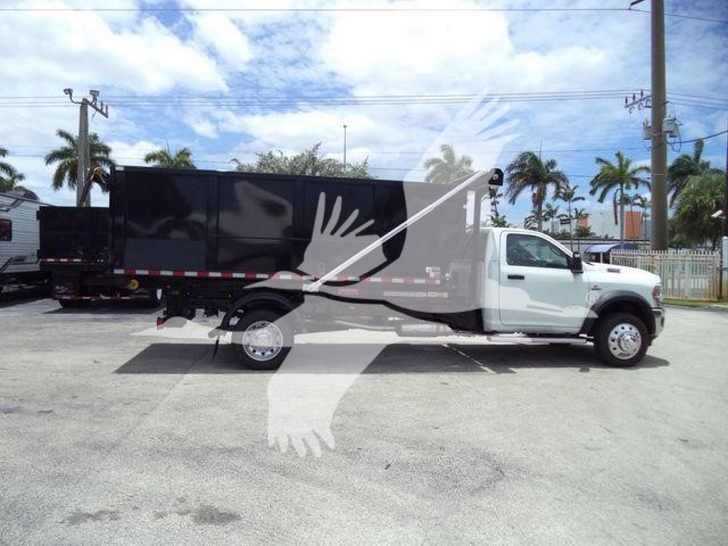 Ram 5500 roll-off truck in side profile with black dump body, white cab, and palm tree background.