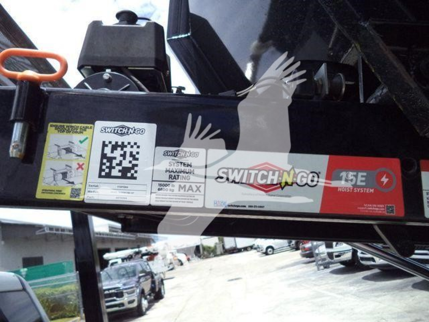 Rolloff truck boom label showing SWITCH-N-GO System label and max rating sticker. Visible text includes SWITCH-N-GO, SYSTEM RATING, 15E, gusts of text and a QR code sticker.
