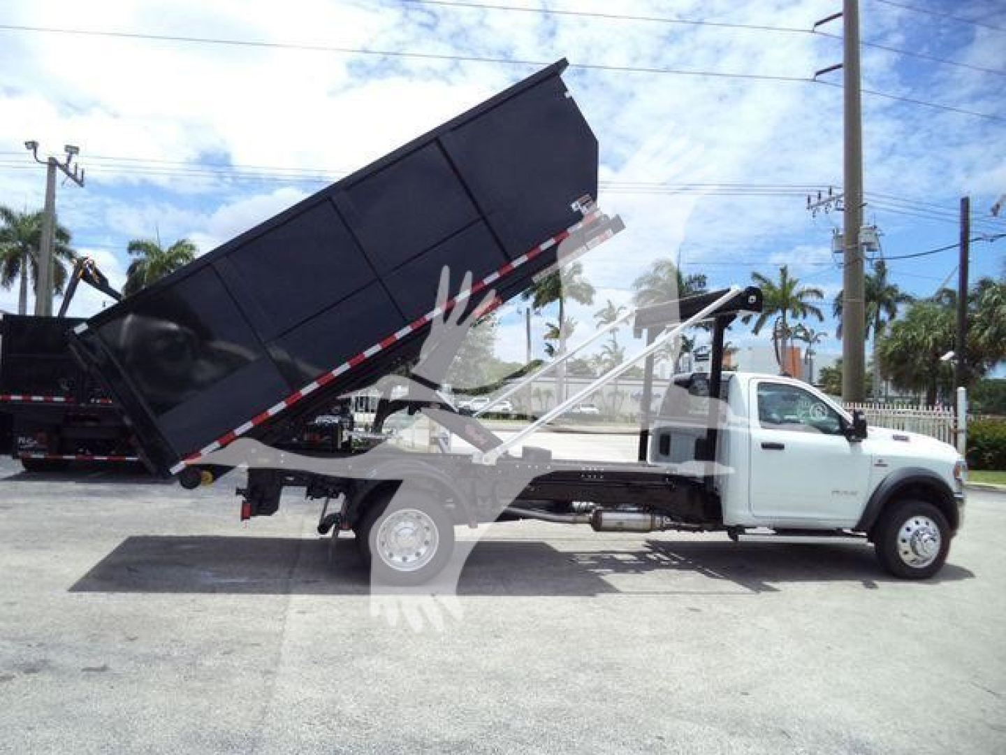 Ram 5500 SLT dump bed truck in a roll-off configuration with white cab and black dump bed.