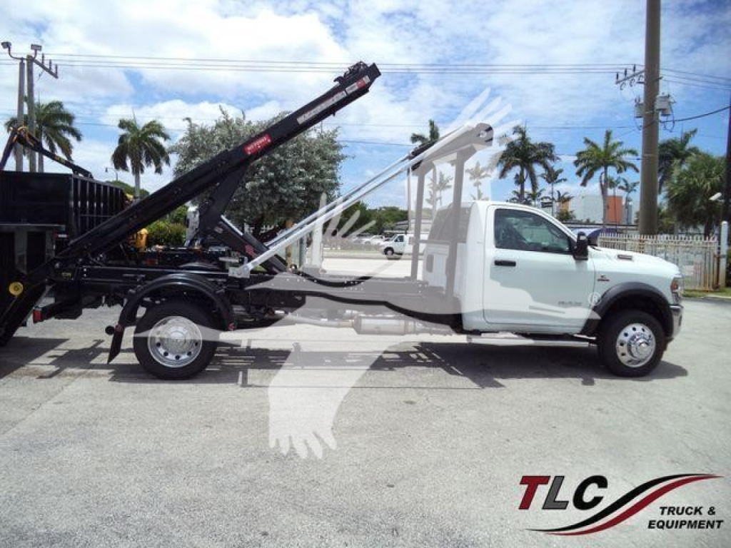 Ram 5500 SLT rollback tow truck side view showing white cab and black wrecking boom with wheel lift.