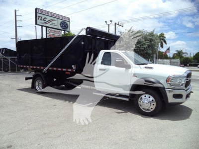 Ram 5500 dump truck with black dump bed, white cab, chrome wheels, and a logo watermark overlay. Visible text includes dealership sign in background with TLC Truck Sales Center, and a banner reading something like 'DSL' on the stock board.