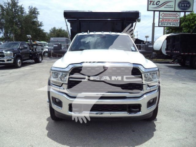Ram 5500 dump truck front view with large grille and RAM emblem, headlights, chrome bumper, and raised dump bed visible in background.