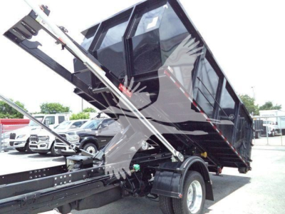 Ram 5500 dump truck bed in elevated position attached to a roll-off body with hydraulic arms visible.