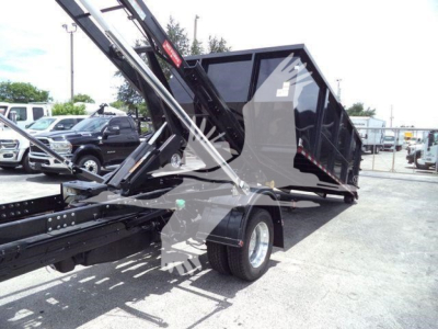 Ram 5500 roll-off truck with black dump bed and hydraulic arm, side view showing rear wheel and trailer hitch.