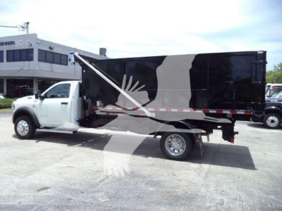 Truck side view showing a white Ram 5500 SLT dump body with black/gray graphic design, stock number DSL550014SNG2, roll-off category, new condition.