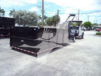 Truck chassis showing a long black rectangular roll-off dumpster body attached to a Ram 5500 SLT pickup with a hydraulic hoist. No visible logos or numbers legible on the body.