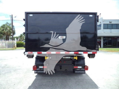 Truck rear showing roll-off container with Ram 5500 SLT branding and bumper lights.