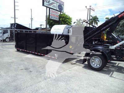 Ram 5500 rollback truck bed with hydraulic crane and black dump bed, wheel and white cab visible, stock yard background.