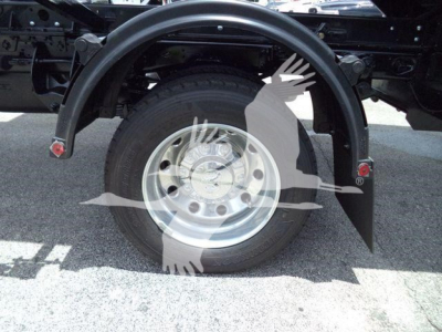 Truck rear wheel and fender showing wheel hub and suspension components.