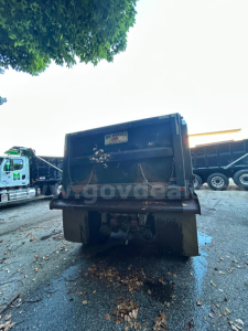 Dump truck bed rear view showing hydraulic dump extends and bumper with tag sticker.