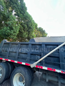 Dump truck bed and wheels of a 2016 Kenworth T370 dump truck showing the side with a long aluminum support bar across the top edge.