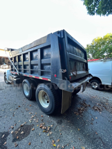 Dump truck rear and side view showing dump bed with dual rear axles on a Kenworth T370 in-service vehicle.