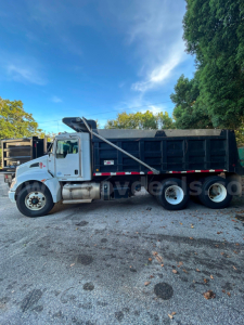 Kenworth T370 dump truck side view showing black dump body and white cab.