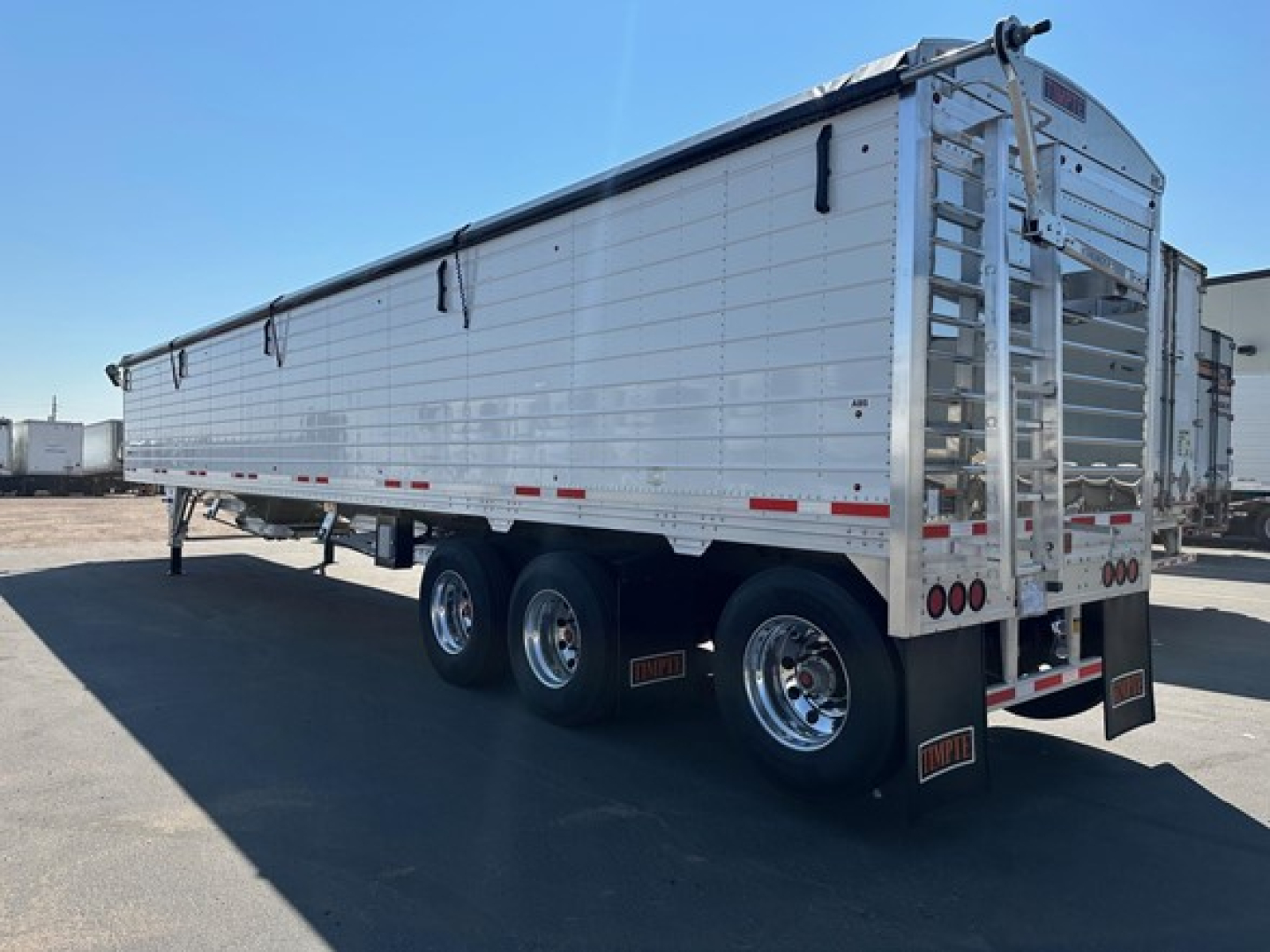 Timpte Super Hopper trailer side and rear view showing aluminum panels and tandem axle wheels with ladder at back.