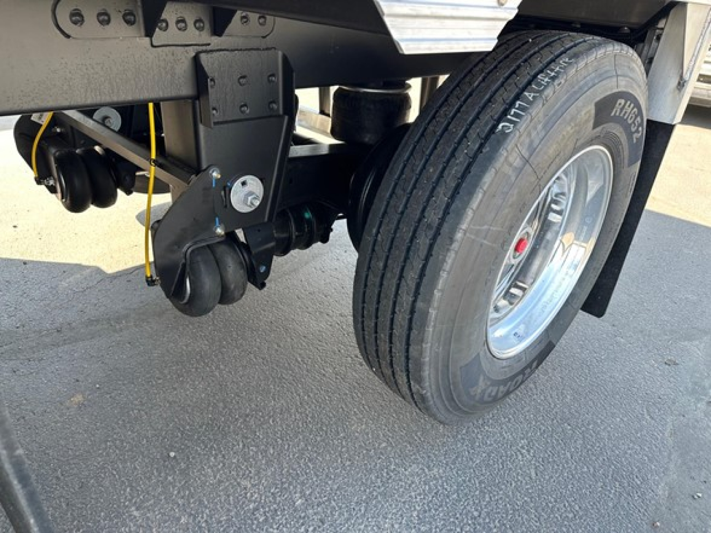Trailer suspension area with dual wheels and undercarriage components visible; includes a pneumatic valve line and leaf spring mount.