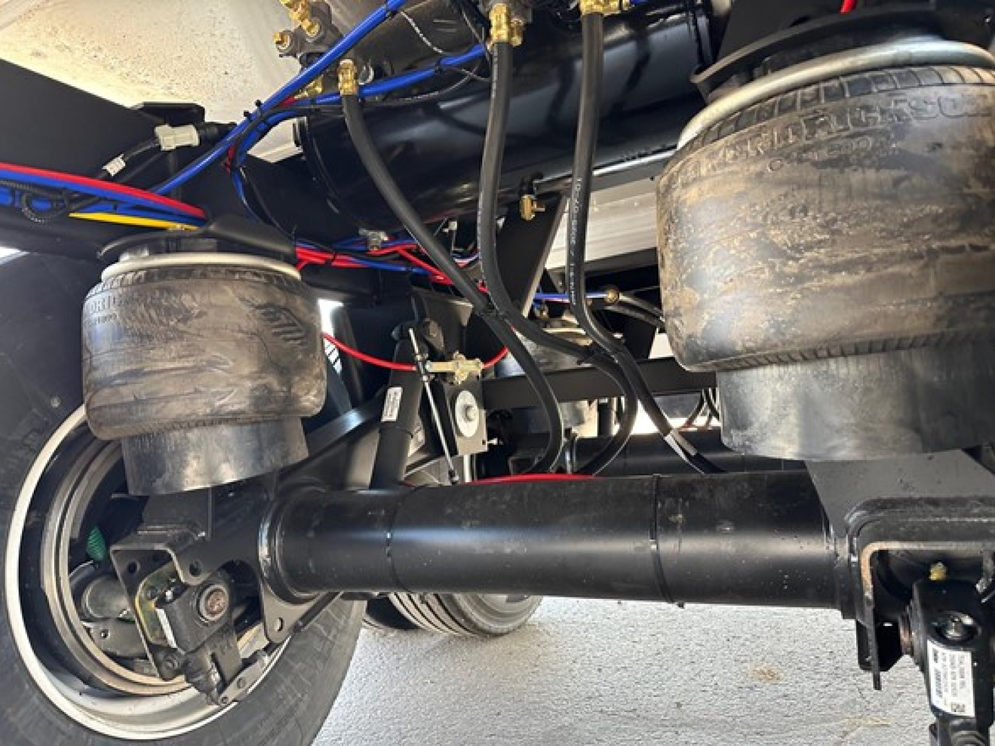 Trailer undercarriage showing air suspension bags, black steel chassis, leaf springs, and hydraulic lines for a Timpte hopper trailer.