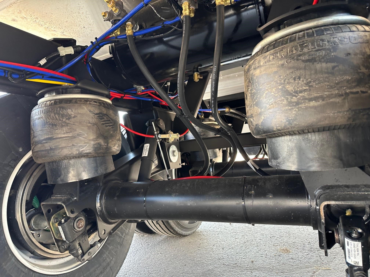 Timpte Super Hopper trailer undercarriage showing air springs, suspension, axles, and hydraulic lines with labels and hoses.
