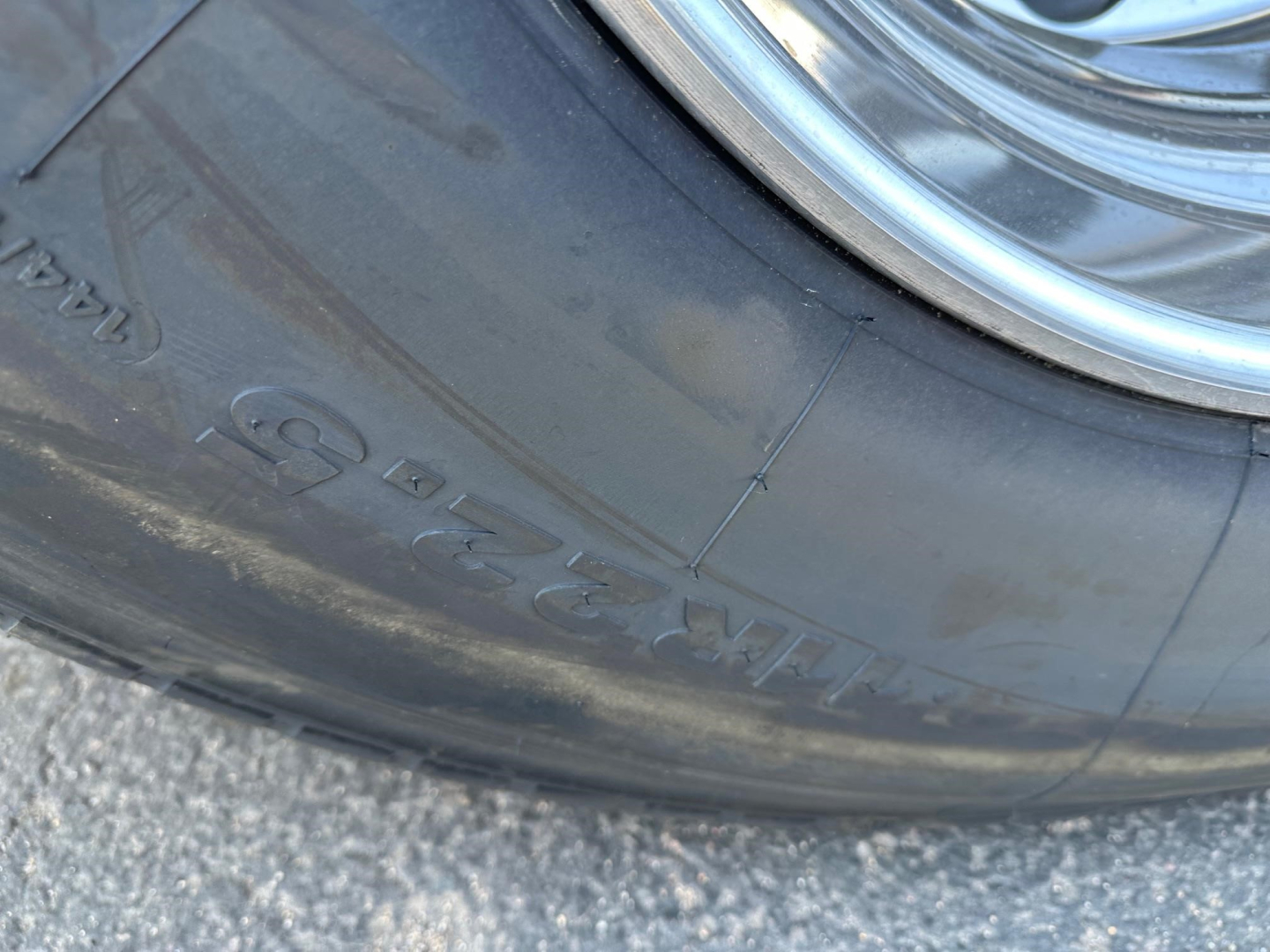 Tire with embossed markings and wheel; visible text includes 'INTERNAL' and numbers along the tire sidewall, with a chrome wheel rim partially visible.