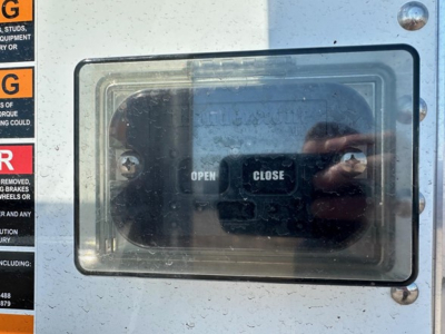 Hopper trailer access door with OPEN and CLOSE labels and reflection of photographer in glass, surrounding stickers visible