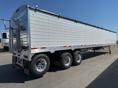 Trailer showing a silver Timpte Super Hopper with triple axles and side panels, viewed from rear-left side.