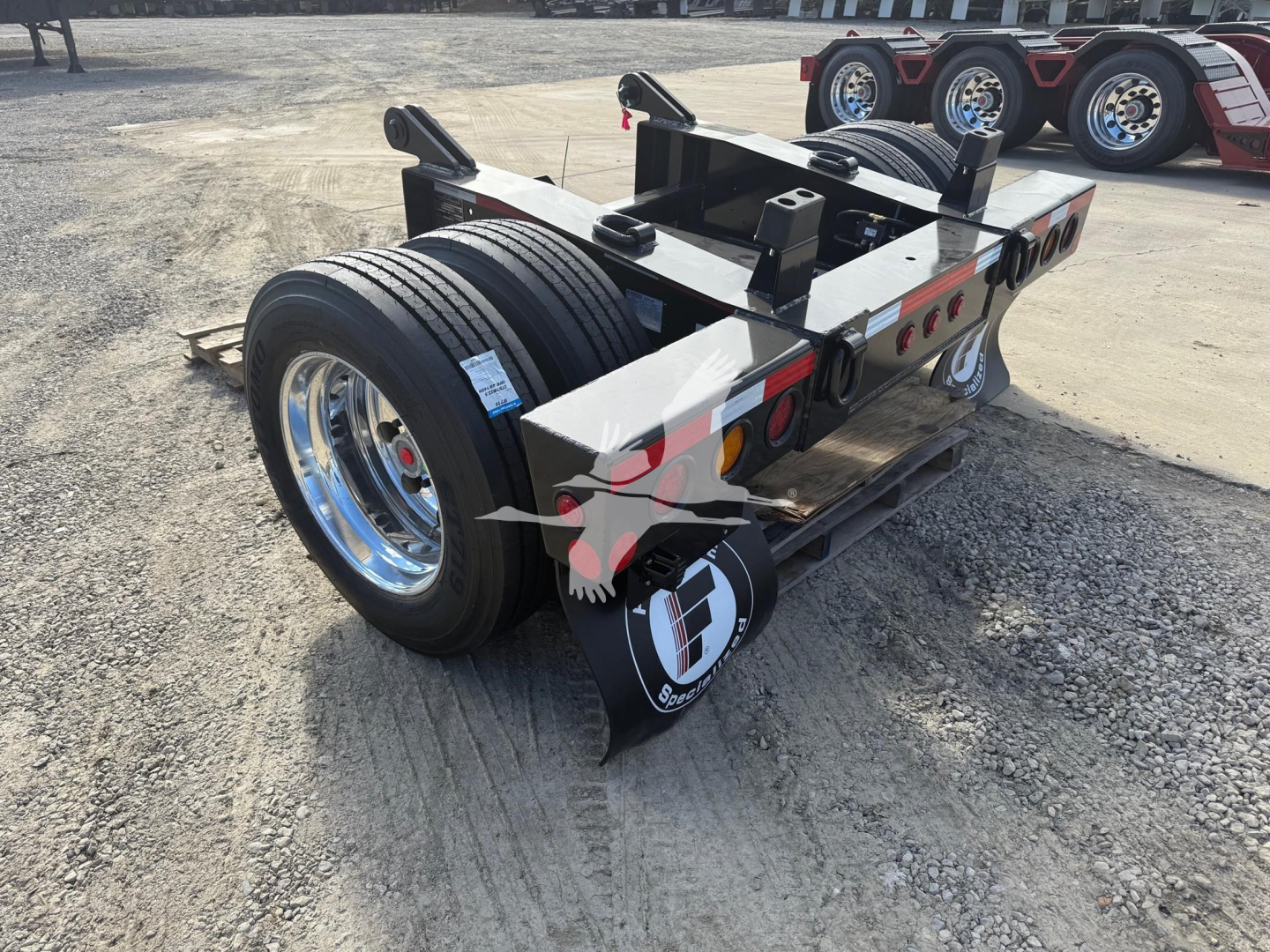 Trailer axle assembly showing twin wheels and flip axle hardware with logoed mudflaps