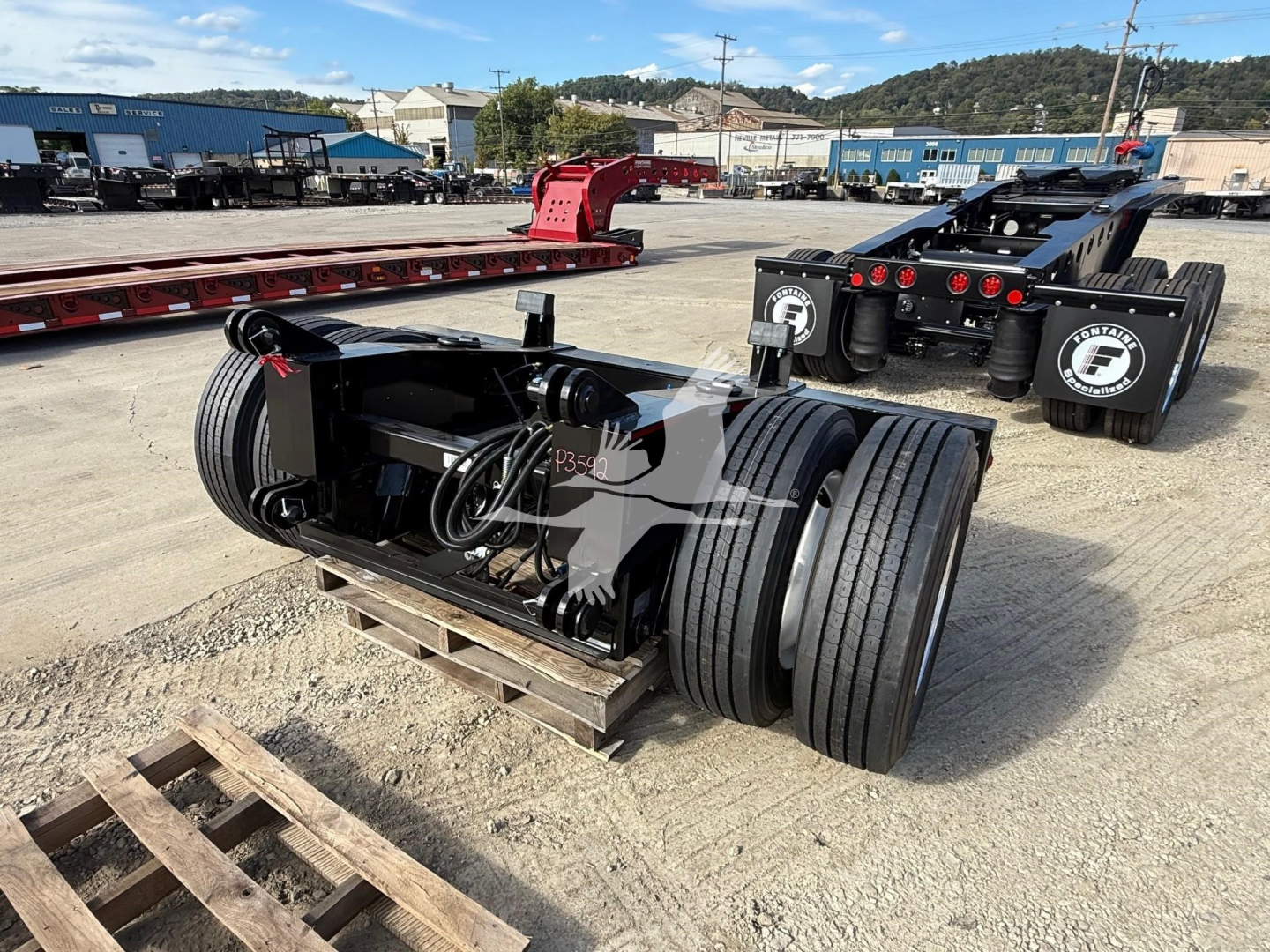 Fontaine flip axle trailer component showing dual large tires and hydraulic control lines with mounting bracket.